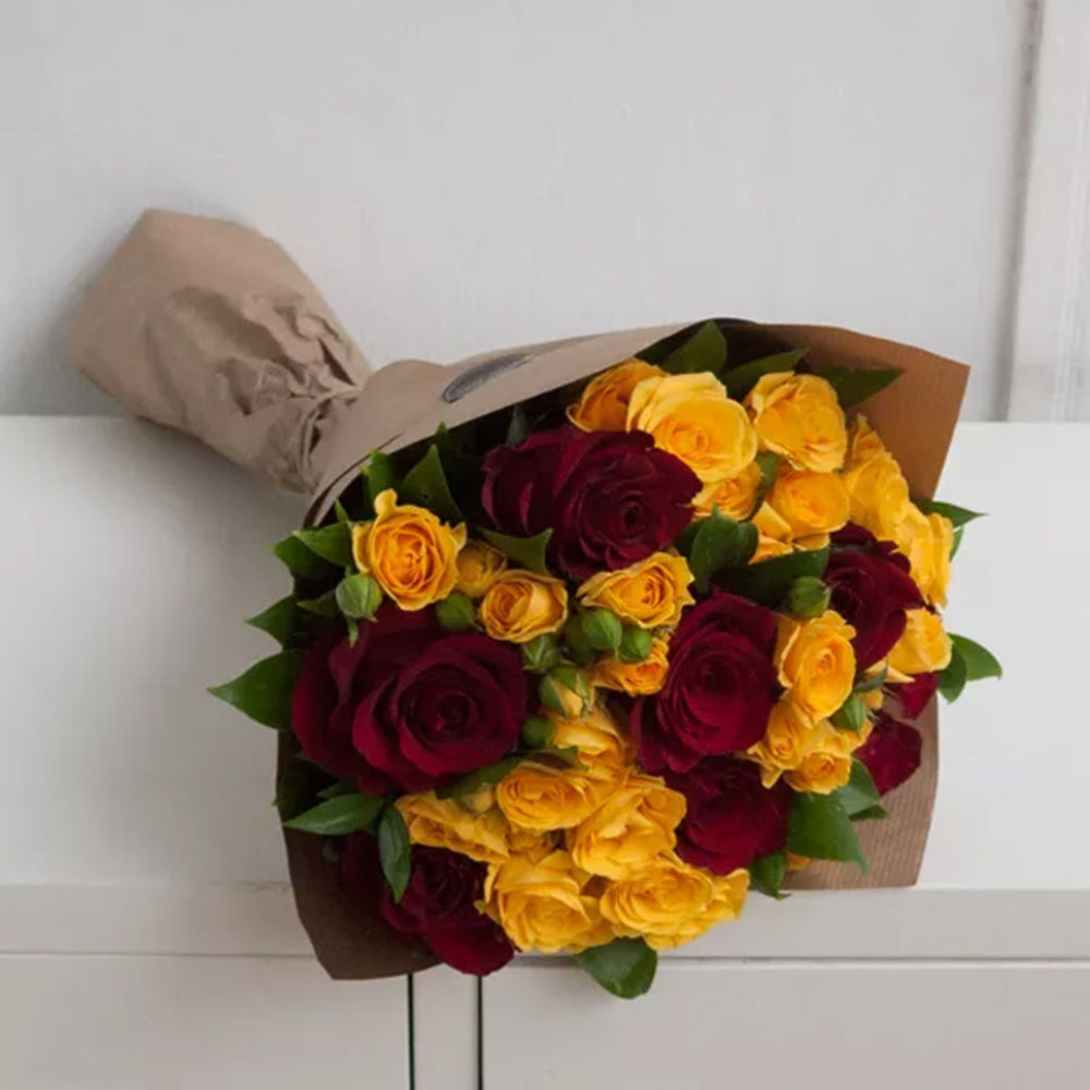 A bouquet of red one headed and yellow spray roses